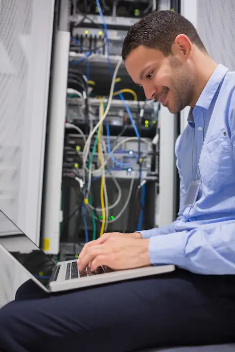A UKNode engineer at a rack in the Manchester data centre, laptop on hand while cabling.