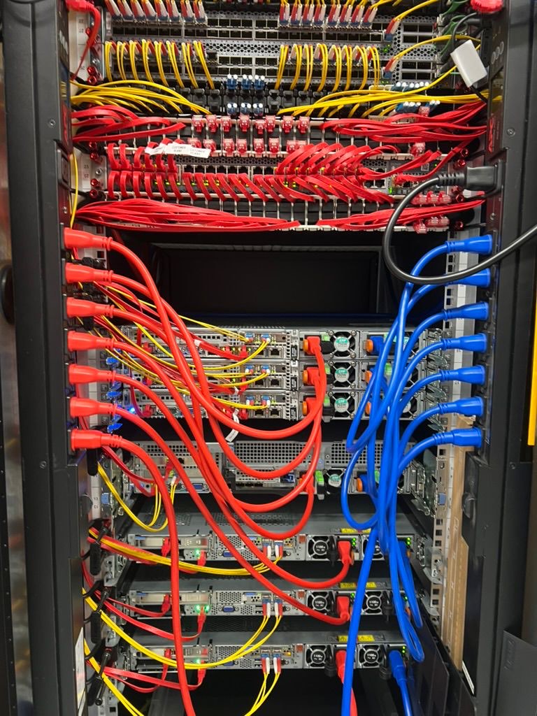 Rear of a UKNode rack in Manchester — patched copper and fibre runs into stacked servers.